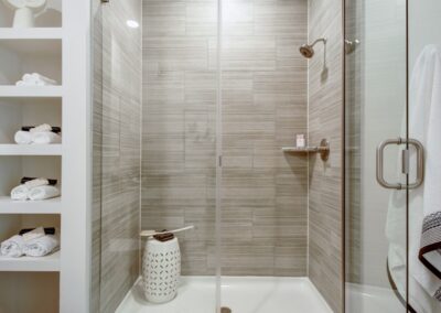 A modern bathroom with a double vanity, a large walk-in shower with glass doors, and elegant tile flooring.