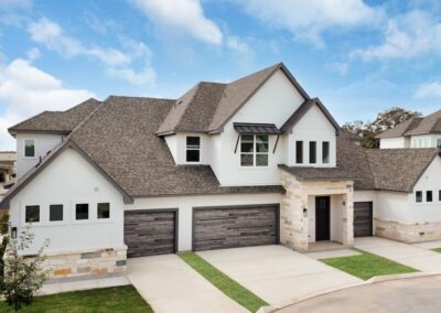 The stunning exterior of a luxury townhome with a two-car garage and a beautifully landscaped private yard.