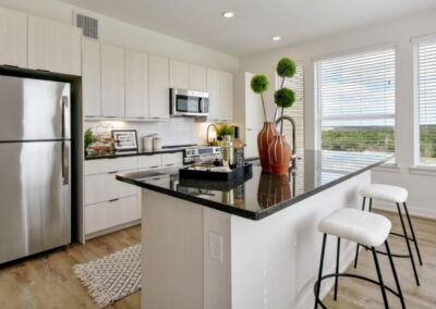 A gourmet kitchen featuring light wood cabinetry, stone countertops, and a modern subway tile backsplash.