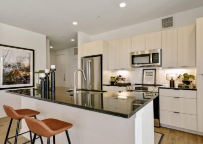 A high-end kitchen with stainless steel appliances, a center island with bar seating, and elegant, light wood cabinetry.