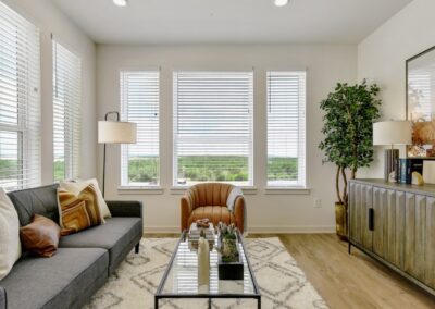 A spacious living room featuring high ceilings, a fireplace, and large windows with abundant natural light.